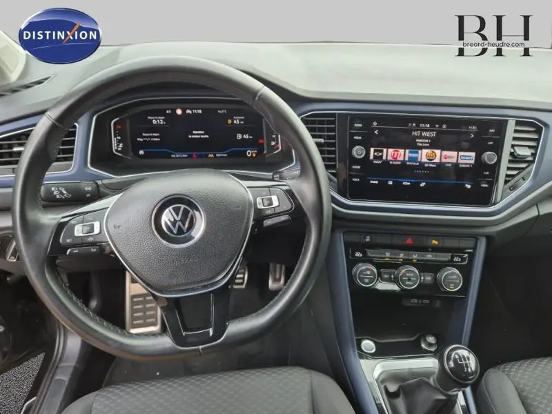 Intérieur du Volkswagen T-Roc gris, vue centrée sur le volant cuir multifonction et l'écran tactile du tableau de bord.