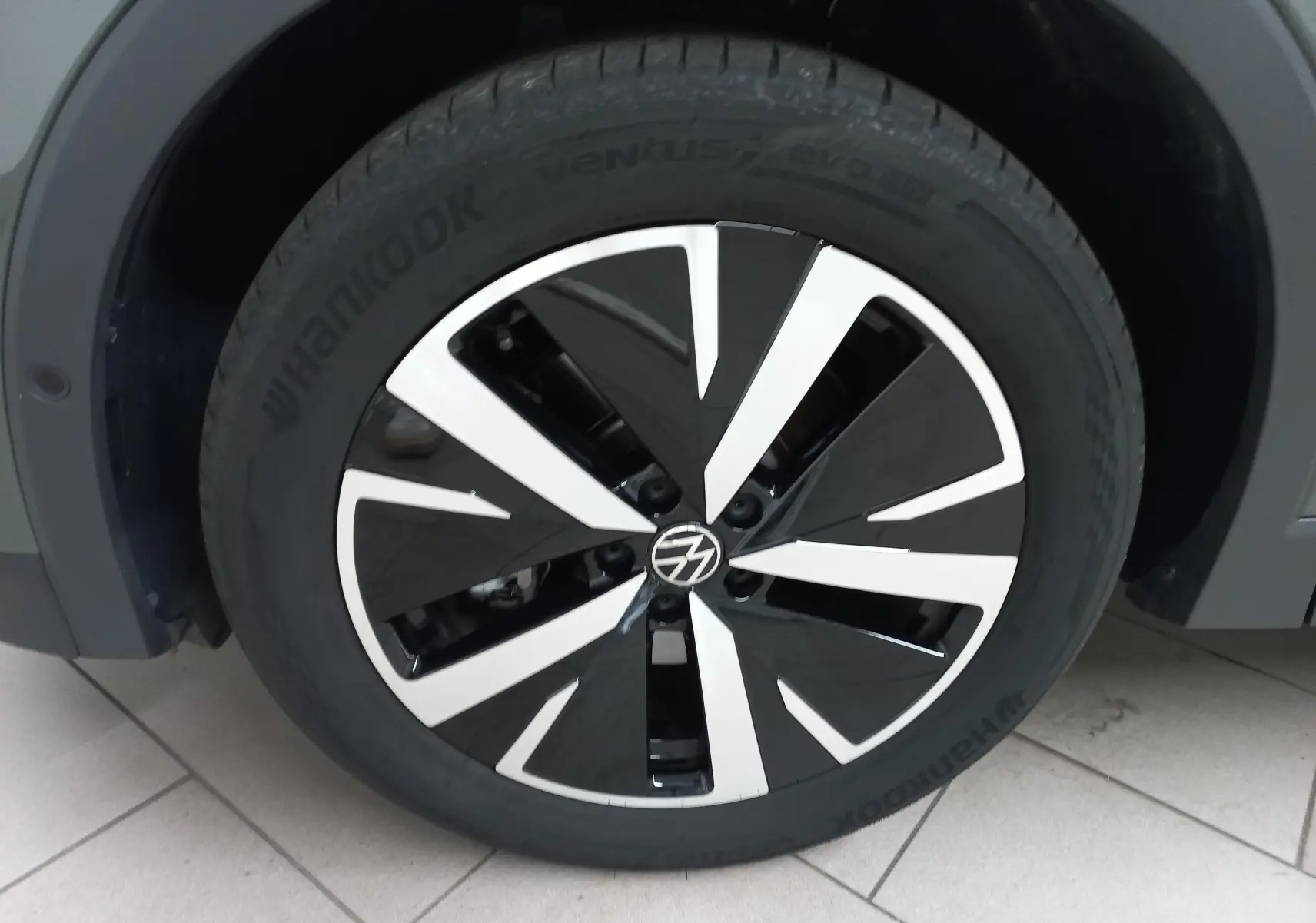 Gros plan sur la jante avant gauche en alliage noir et argent du Volkswagen Tiguan 2025 Vert Cipressino.