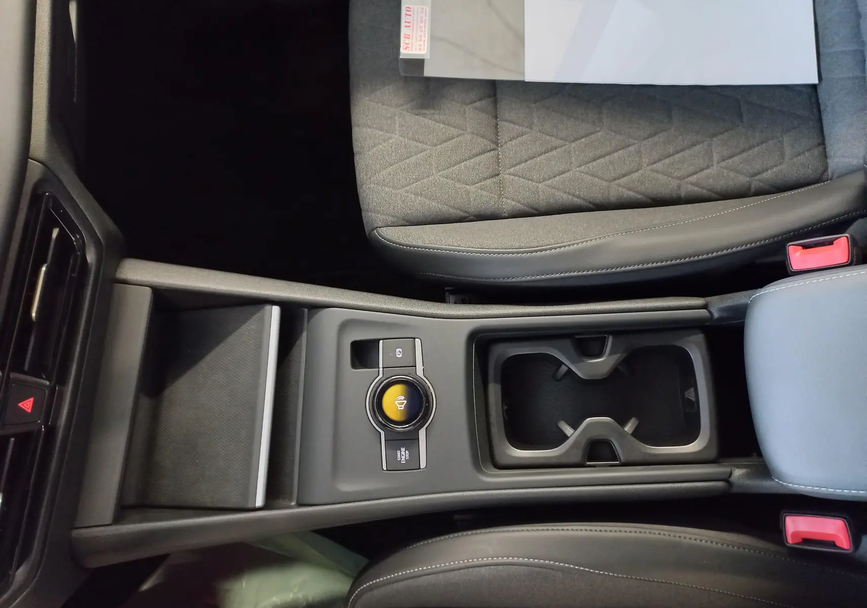 Vue plongeante sur la console centrale du Volkswagen Tiguan 2025, avec porte-gobelets et siège tissu gris à motifs géométriques.