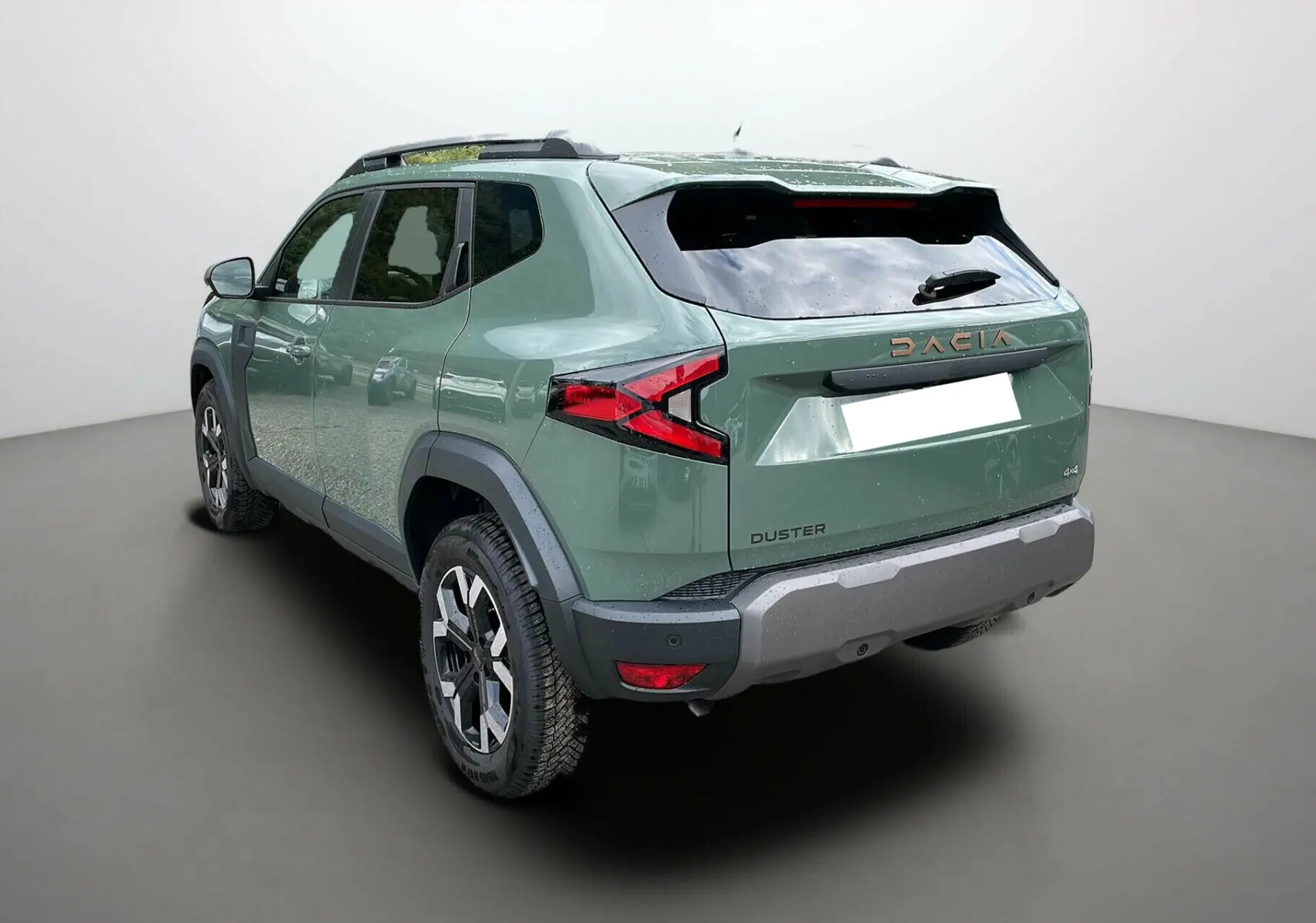 Vue 3/4 arrière droite du Dacia Duster 2025 kaki lichen avec barres de toit et jantes alu 17 pouces.