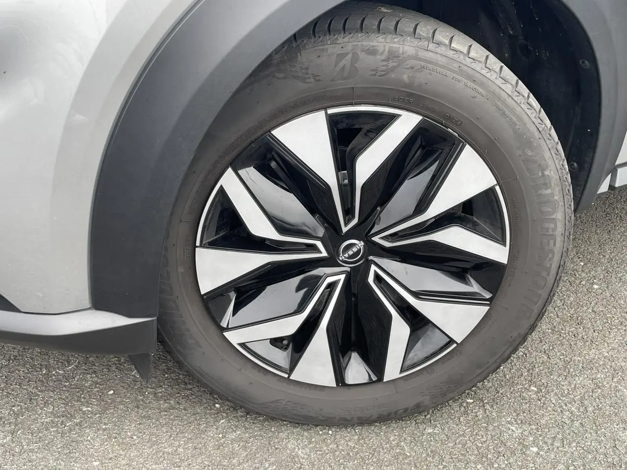 Gros plan sur la roue avant gauche du Nissan Juke 2024 gris Silver, avec jante alliage bicolore noire et argentée.