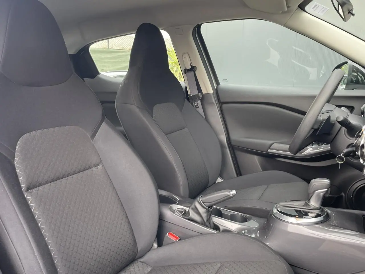 Vue intérieure côté droit des sièges avant noirs et de la console centrale du Nissan Juke 2024 gris Silver.