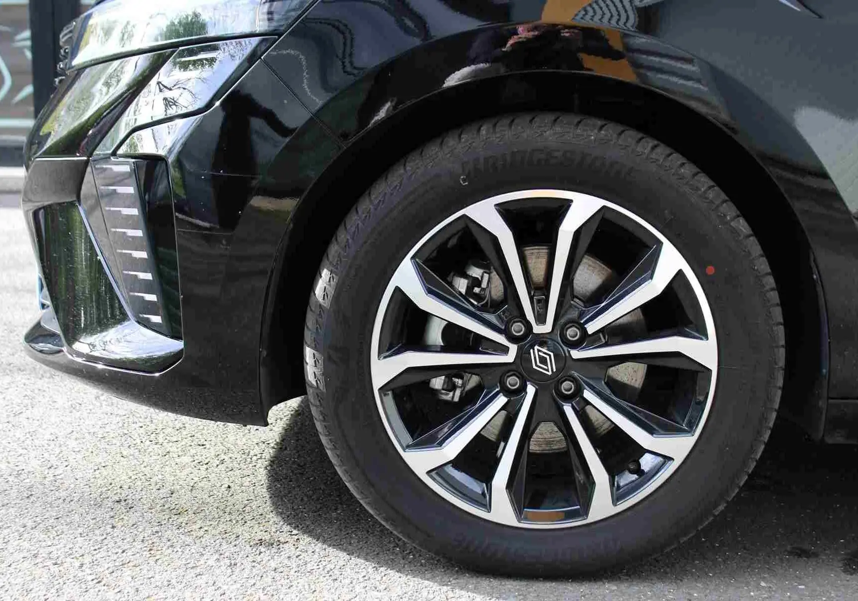 Gros plan sur la roue avant gauche noire étoile métal d’une Renault Clio 2025 avec jante alliage bicolore.