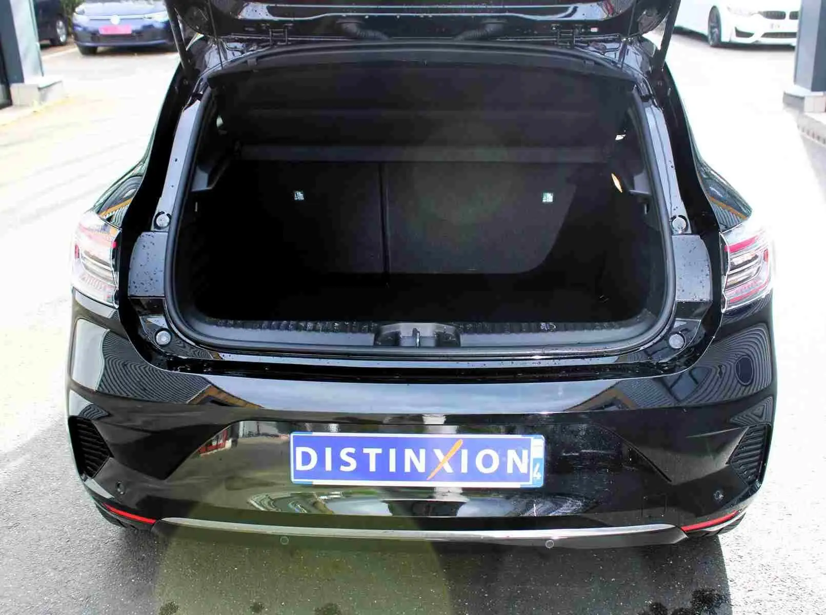 Vue arrière de la Renault Clio noire étoile métal 2025 avec coffre ouvert et feux arrière LED visibles.