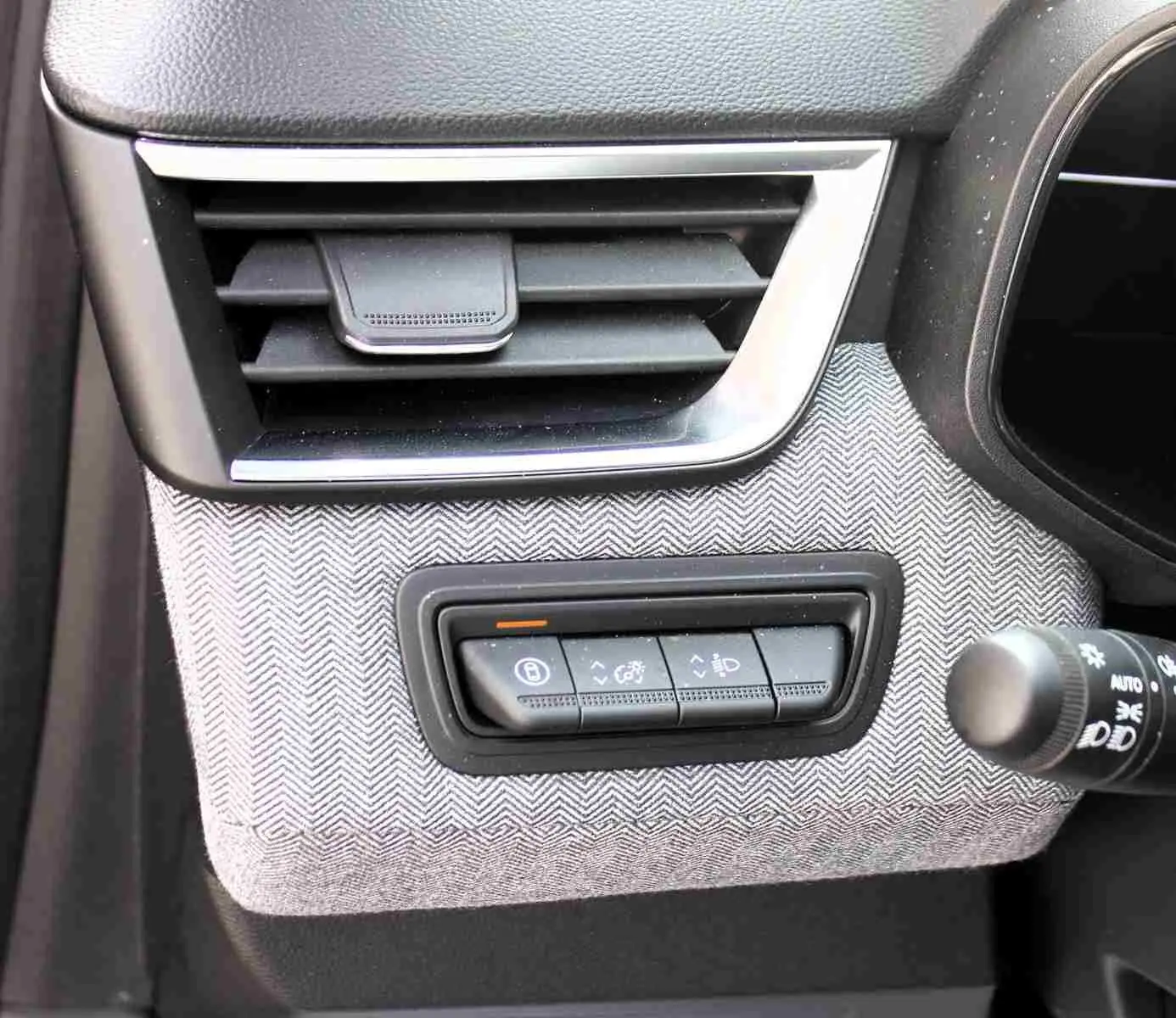 Détail intérieur de la Renault Clio 2025, panneau de commandes sous la sortie d'air avec finition tissu gris clair.