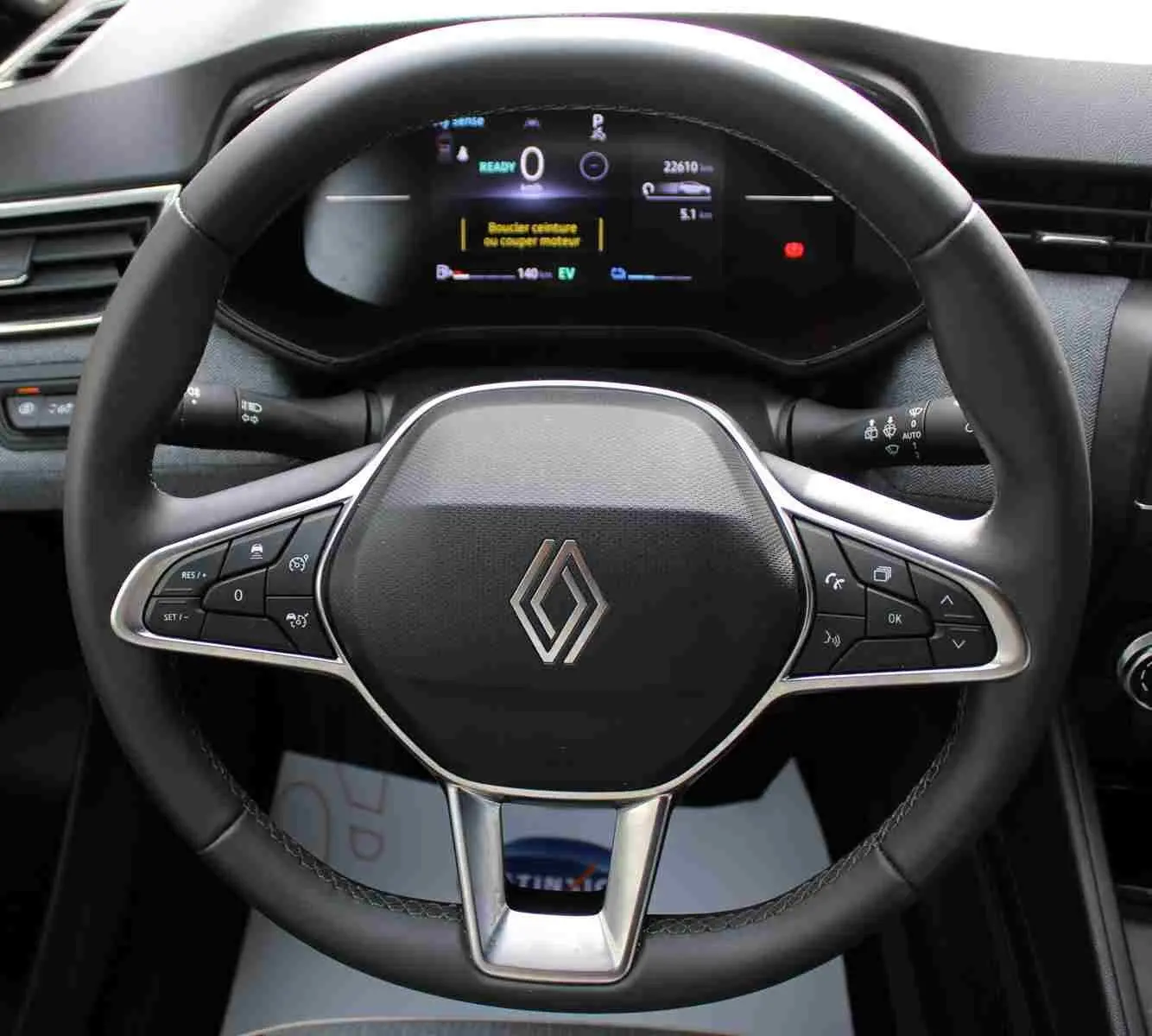 Vue rapprochée du volant noir de la Renault Clio 2025 avec commandes intégrées et tableau de bord numérique allumé.