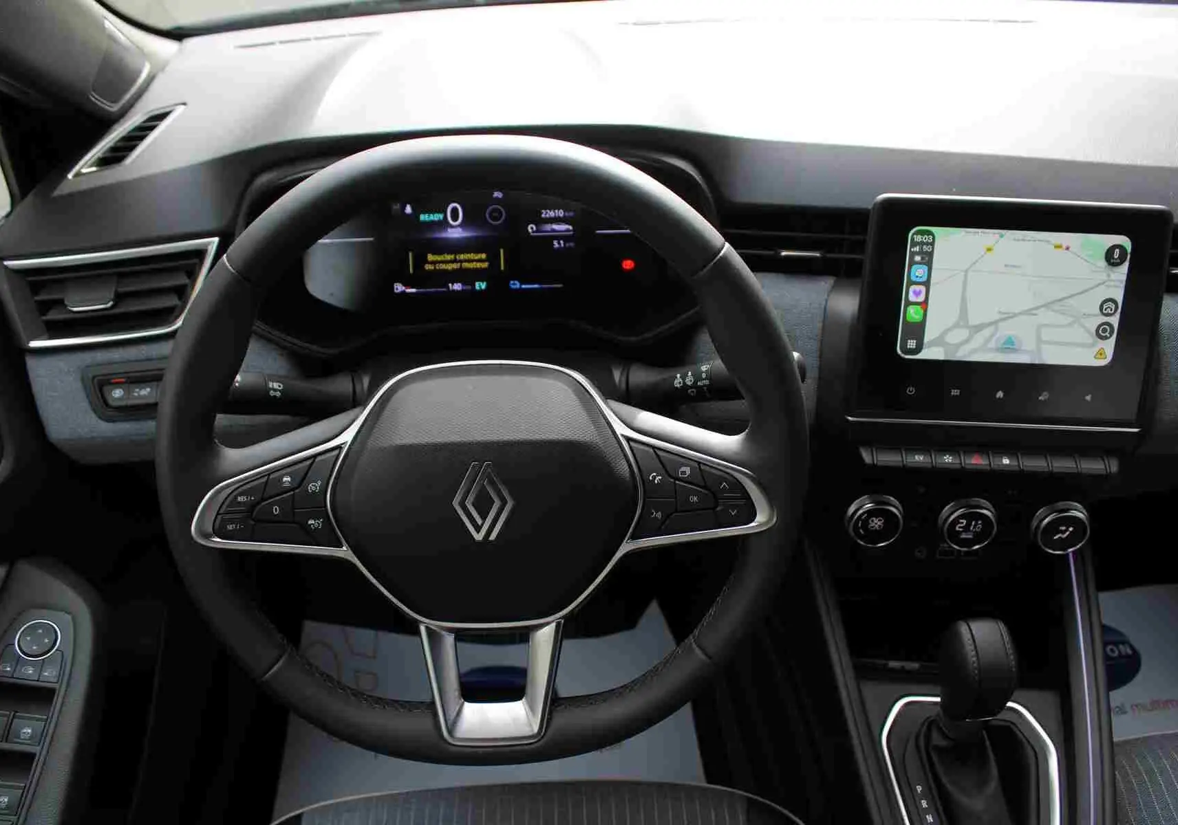 Vue intérieure centrée sur le volant et tableau de bord de la Renault Clio noire, avec écran tactile et commandes au volant.