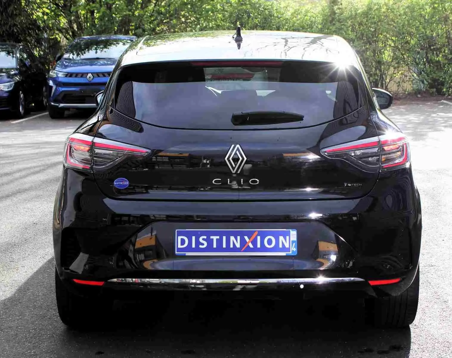 Vue arrière d'une Renault Clio noire étoile métal 2025 avec logo distinctif et plaque "DISTINXION" visible.