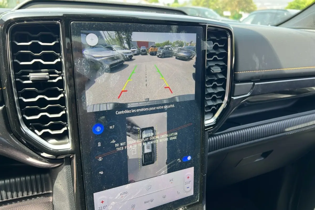 Vue intérieure du tableau de bord du Ford Ranger 2025 avec écran tactile affichant la caméra de recul et les commandes climatisation.