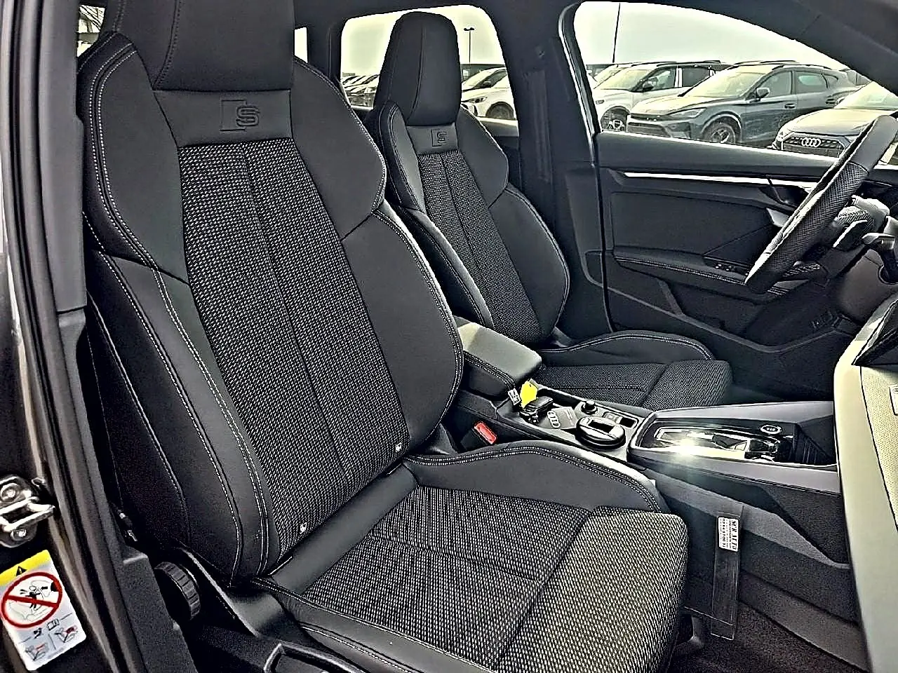 Vue intérieure côté gauche montrant les sièges sport noirs avec logo S et console centrale d'une Audi A3 Sportback 2026.