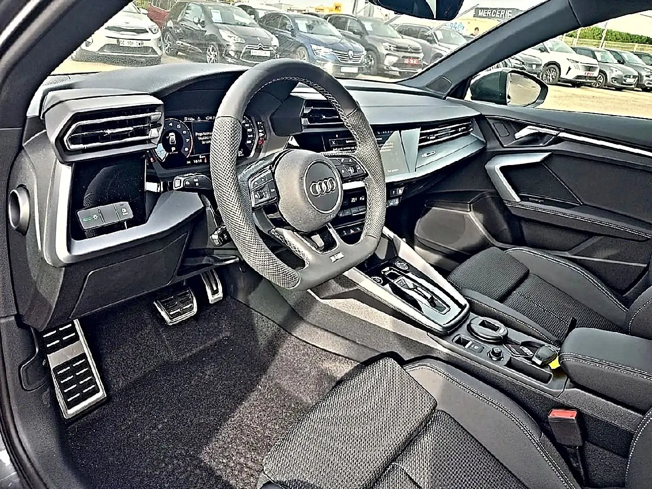 Intérieur Audi A3 Sportback 2026 vu côté conducteur, volant cuir sport et console centrale moderne noire.