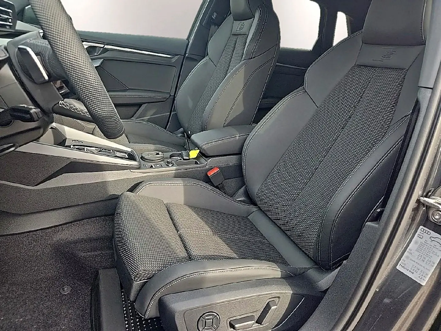 Vue intérieure côté conducteur de l’Audi A3 Sportback 2026 avec sièges sport noirs et volant cuir multifonction.