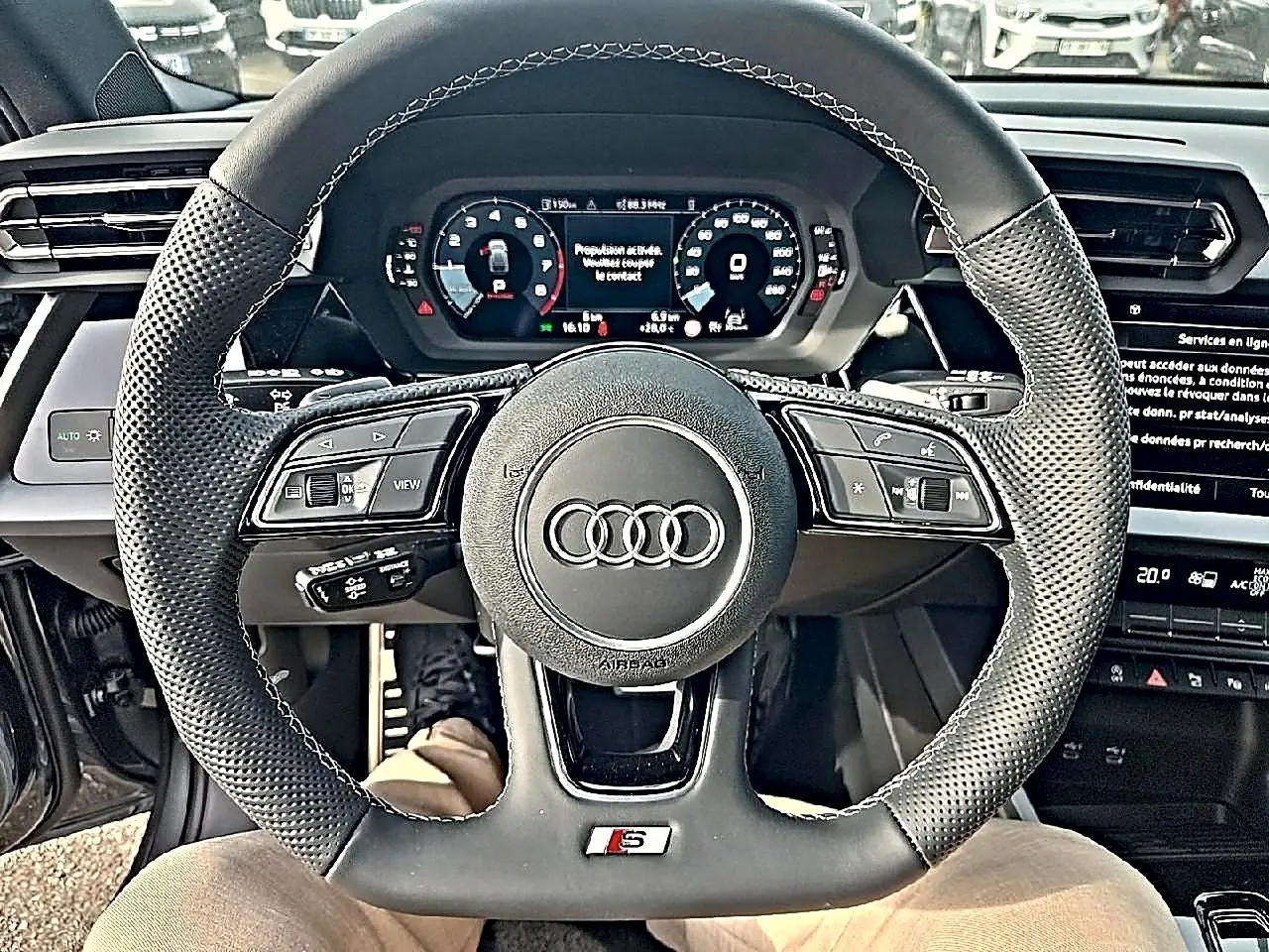 Vue centrée sur le volant sport noir perforé avec logo Audi et tableau de bord digital de l'Audi A3 Sportback 2026.
