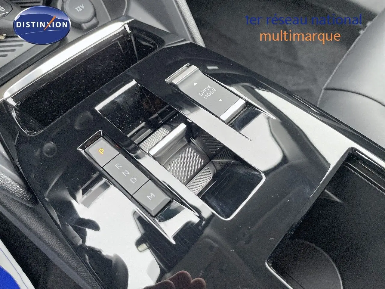 Gros plan sur la console centrale noire brillante de la Citroën C4 blanche 2024, mettant en valeur le sélecteur de boîte auto et le bouton Drive Mode.