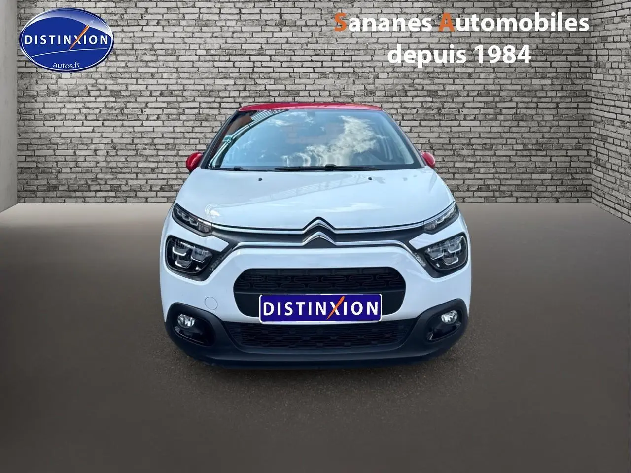 Vue frontale d'une Citroën C3 2023 blanche avec toit rouge, calandre noire et projecteurs antibrouillard visibles.