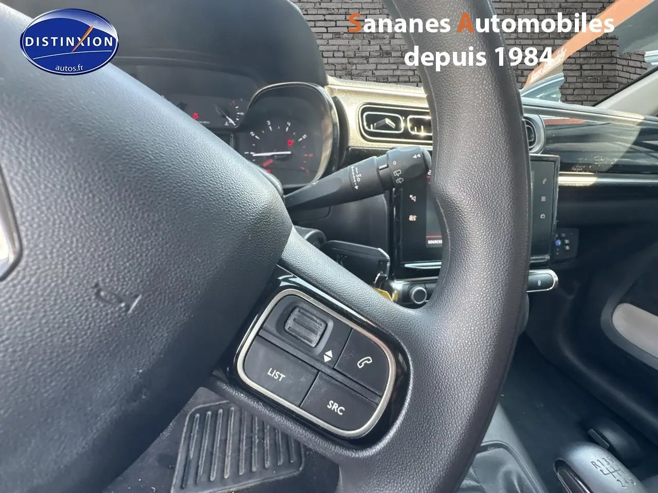 Gros plan sur les commandes audio au volant d'une Citroën C3 blanche de 2023, intérieur moderne avec tablette tactile.