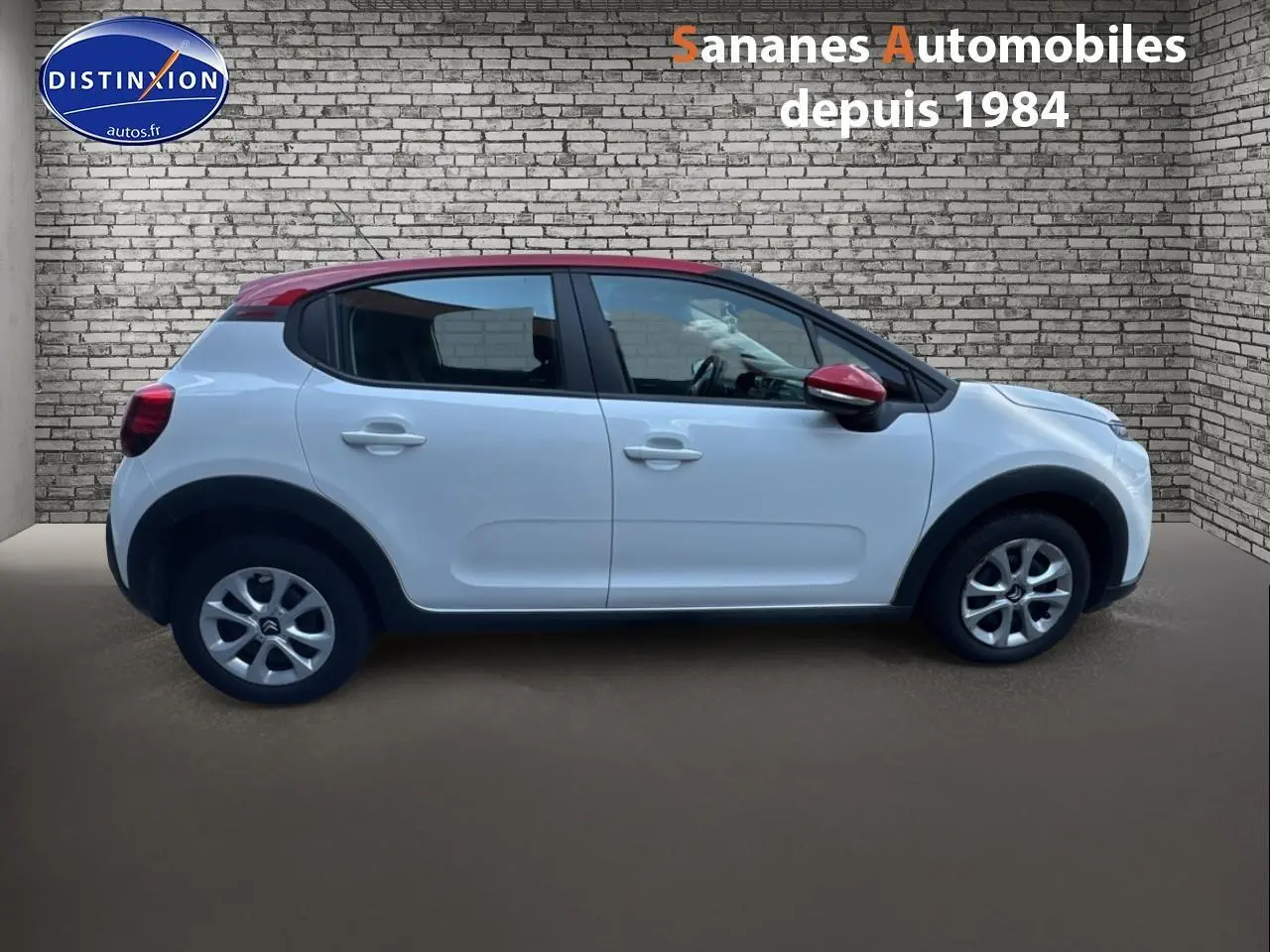 Profil côté gauche d'une Citroën C3 2023 blanc banquise avec toit et rétroviseur rouge, élargisseurs d'ailes noirs.