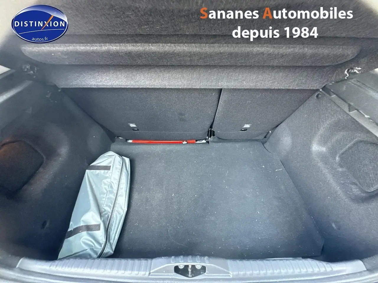 Coffre ouvert d'une Citroën C3 blanche 2023, vue de dessus montrant un sac gris à gauche et un intérieur noir.
