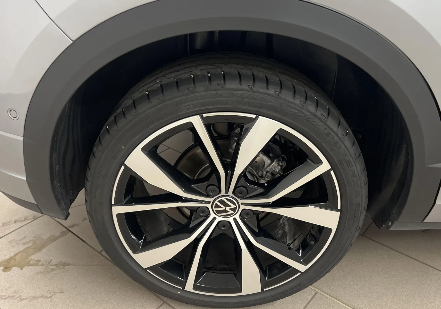 Gros plan sur la jante 19 pouces Misano bicolore noir et argent du Volkswagen T-Roc gris pyrite côté arrière droit.