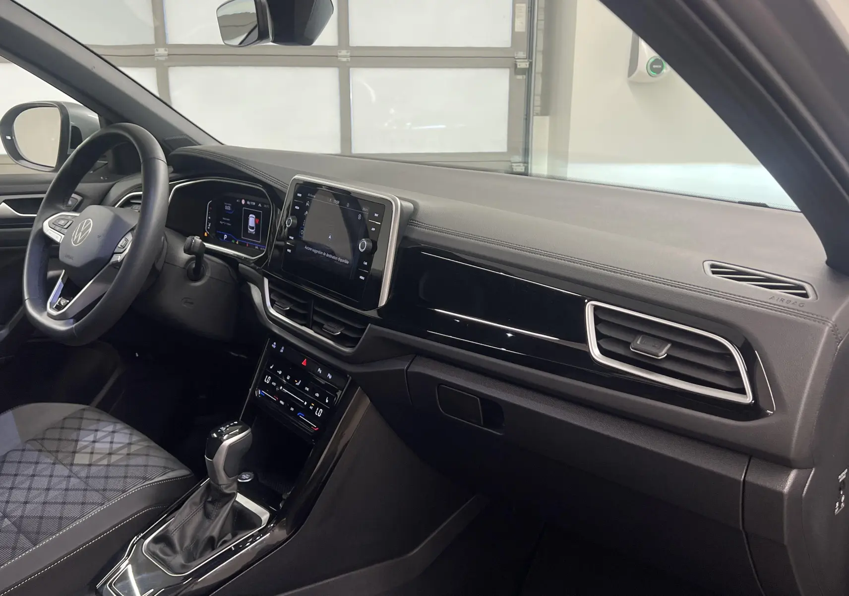 Intérieur avant droit du Volkswagen T-Roc 2024, tableau de bord moderne avec écran tactile et volant multifonction.