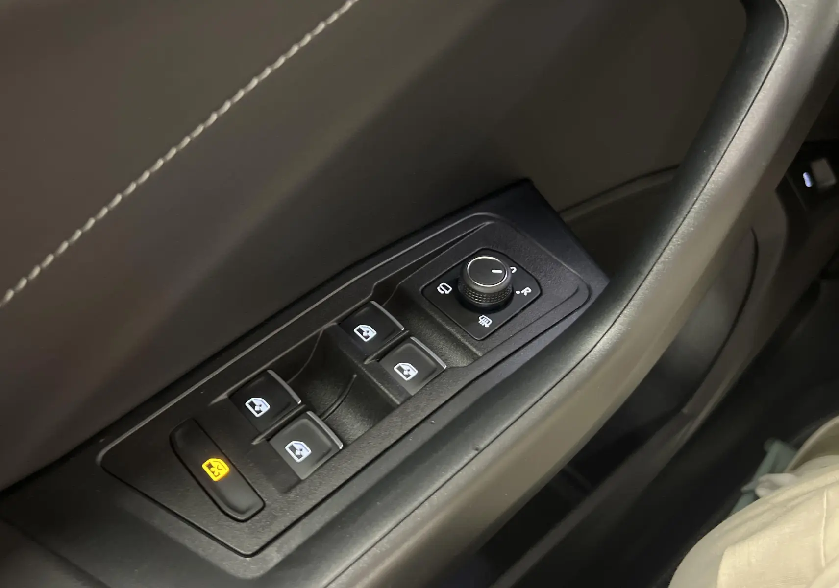 Gros plan sur les commandes de lève-vitres et rétroviseurs côté gauche du Volkswagen T-Roc 2024 finition R-Line.