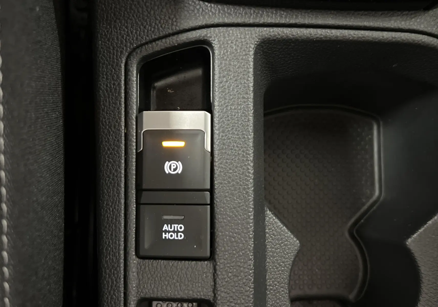 Gros plan sur la commande de frein de parking électronique et bouton Auto Hold dans le Volkswagen T-Roc 2024.