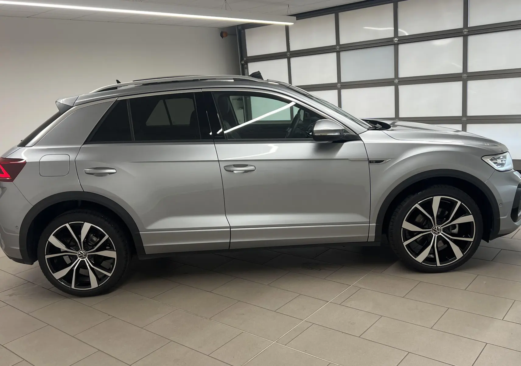 Volkswagen T-Roc 2024 gris pyrite vu de profil côté gauche avec jantes 19 pouces et toit ouvrant panoramique.