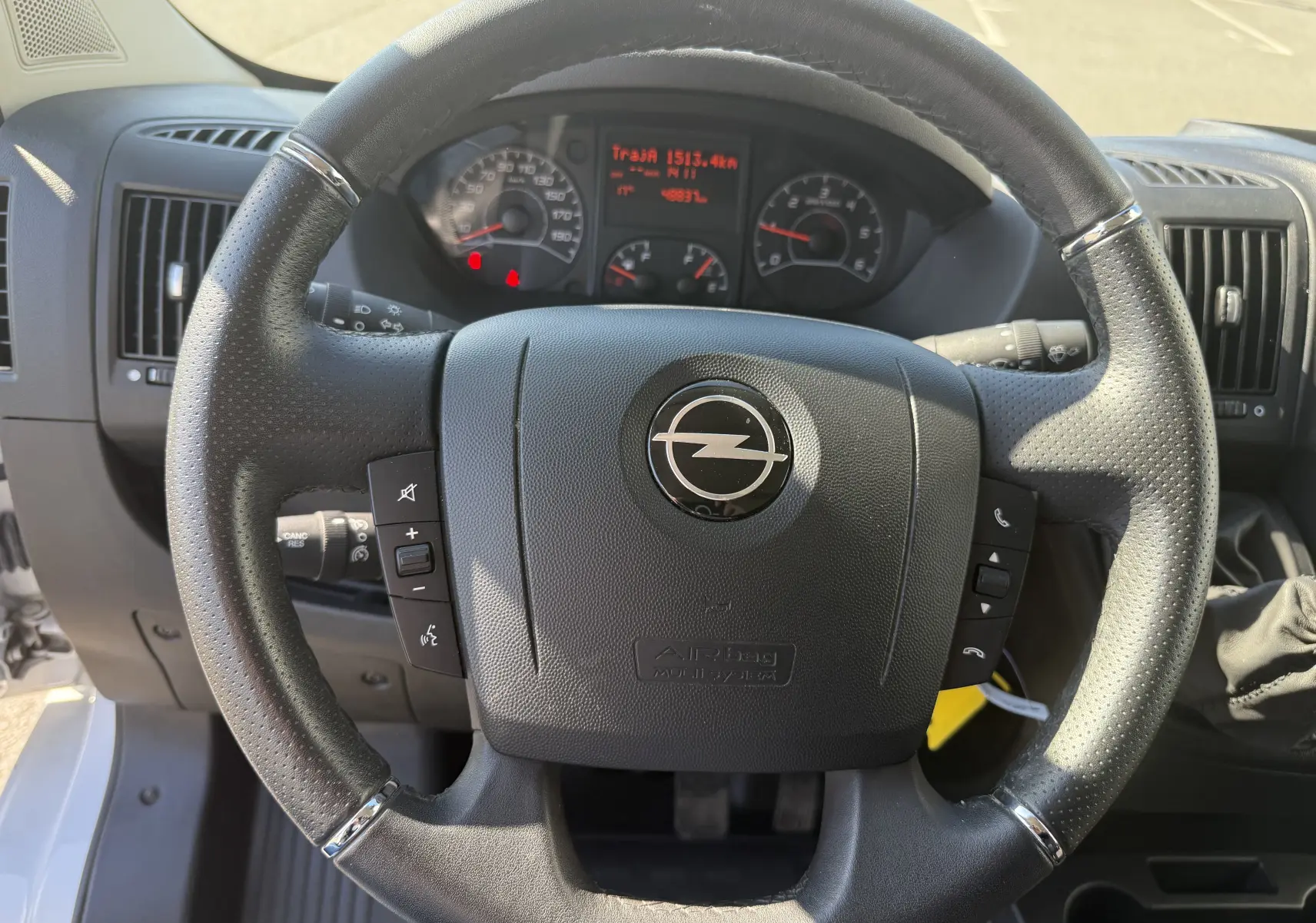 Vue rapprochée du volant noir de l’Opel Movano Fourgon 2023 avec tableau de bord et commandes intégrées visibles.