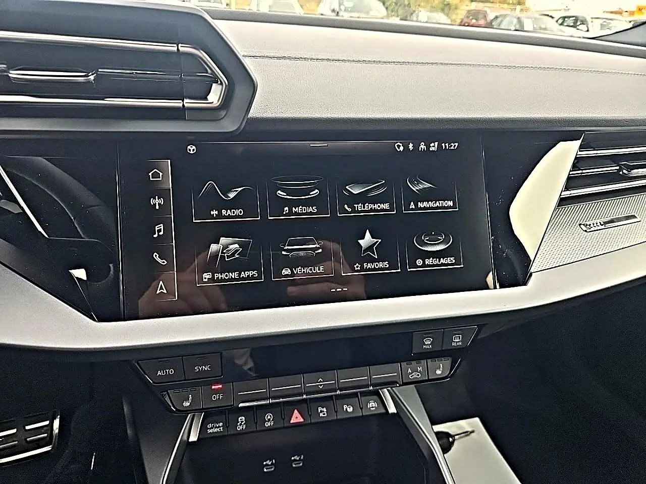 Vue rapprochée de la console centrale de l'Audi A3 Sportback 2026, écran tactile et commandes climatisation visibles.