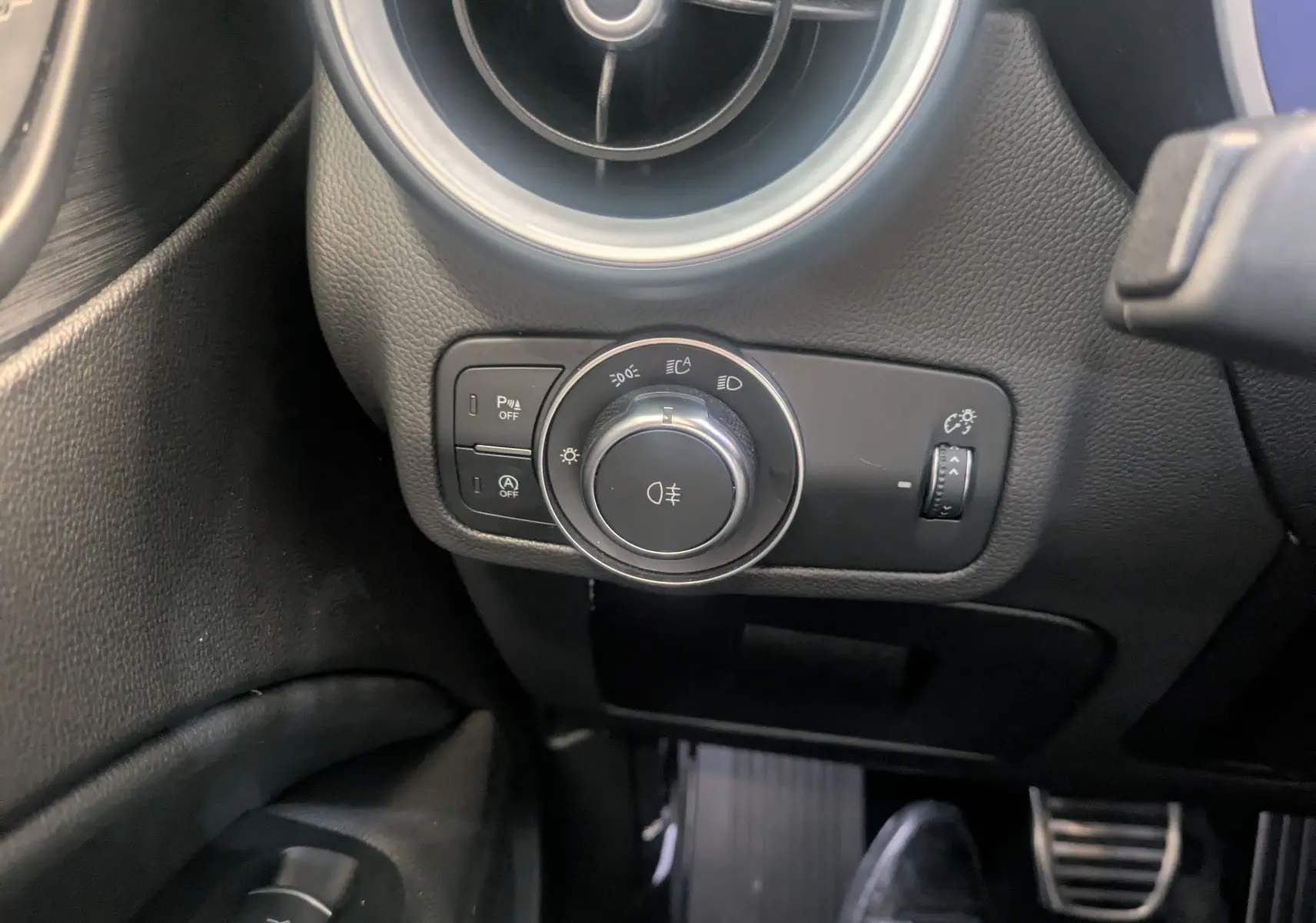 Gros plan sur le bouton de commande des phares et la ventilation côté gauche de l'Alfa Romeo Stelvio blanc 2023.