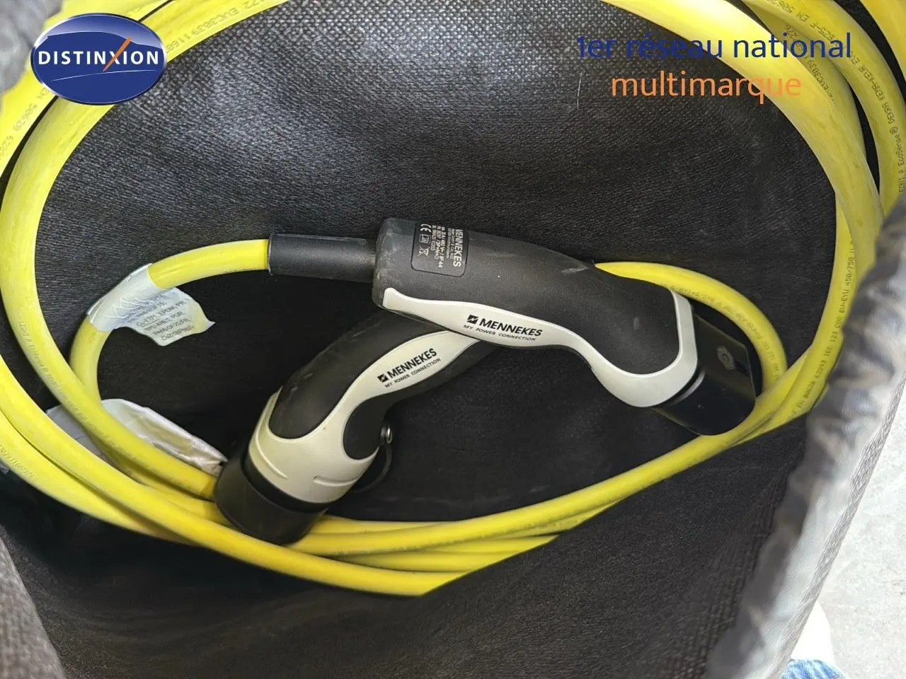 Gros plan sur câble de recharge jaune avec connecteurs Mennekes dans le coffre d'un CUPRA Formentor noir minuit hybride rechargeable.