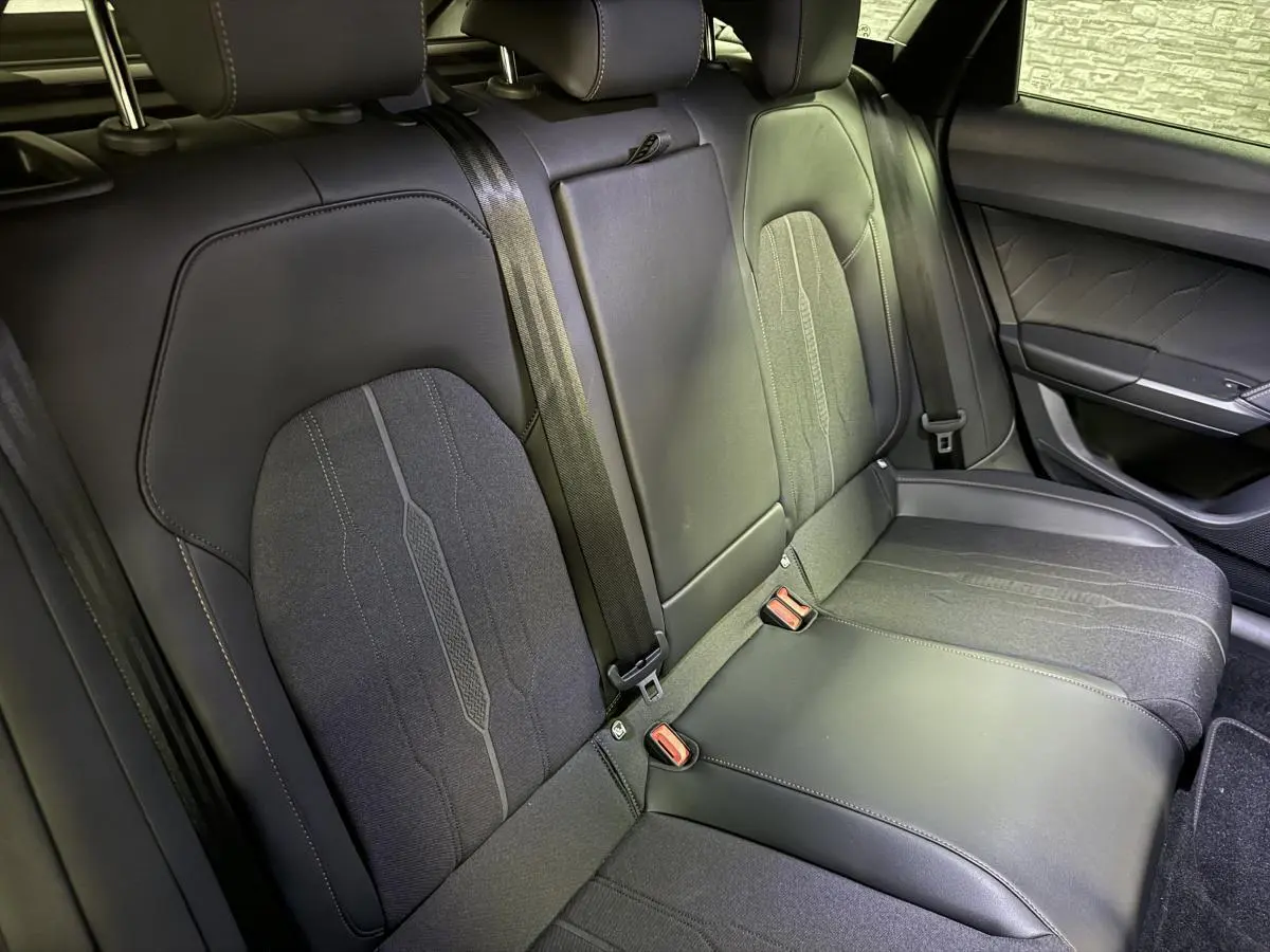 Vue rapprochée des sièges arrière noirs en similicuir et tissu du CUPRA Leon Sportstourer 2024 avec ceintures de sécurité visibles.