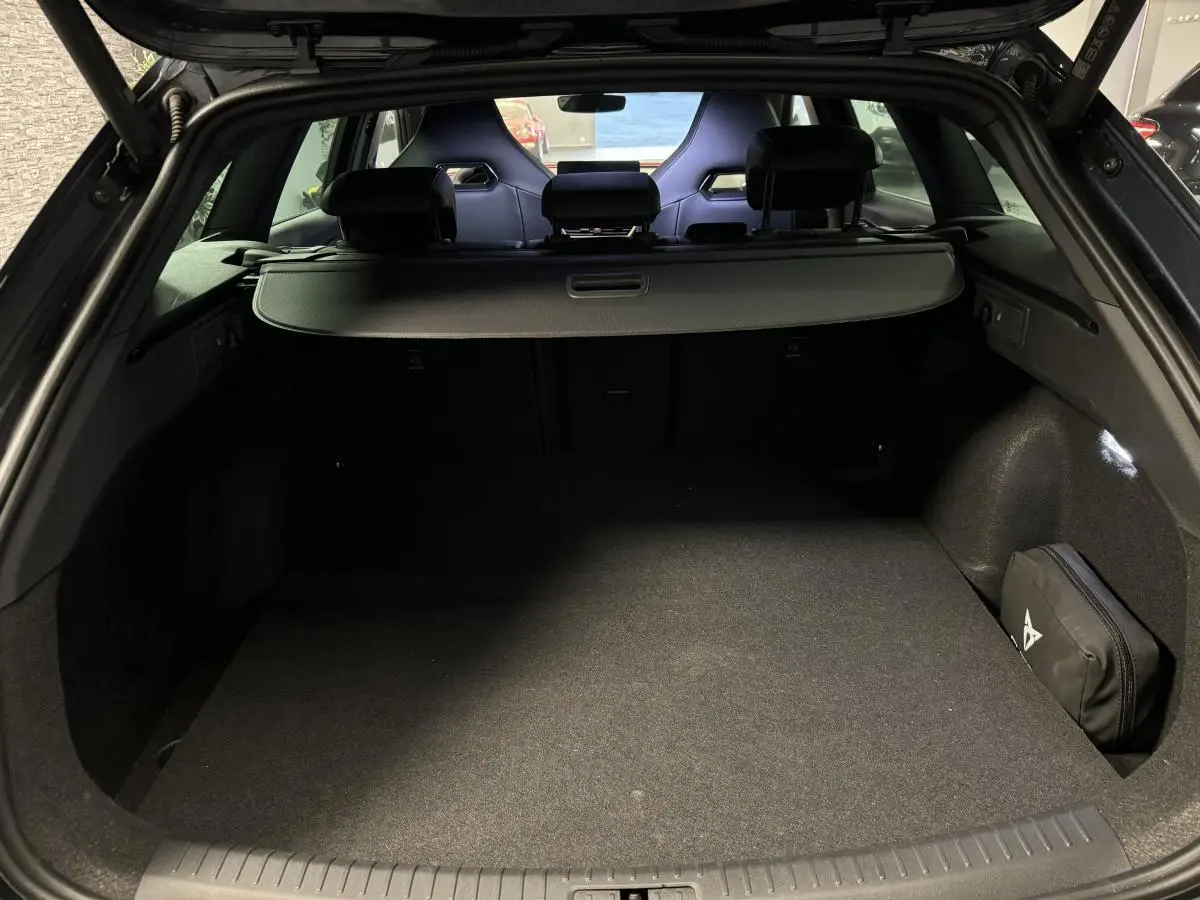 Coffre ouvert du CUPRA Leon Sportstourer gris, vue arrière montrant l'espace de chargement et les sièges baquets noirs.