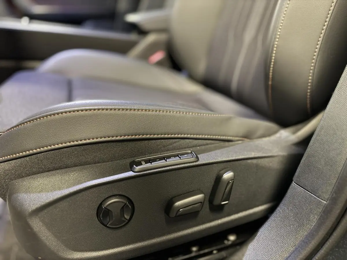 Gros plan sur les commandes de réglage électrique du siège avant droit du CUPRA Leon Sportstourer gris 2024.