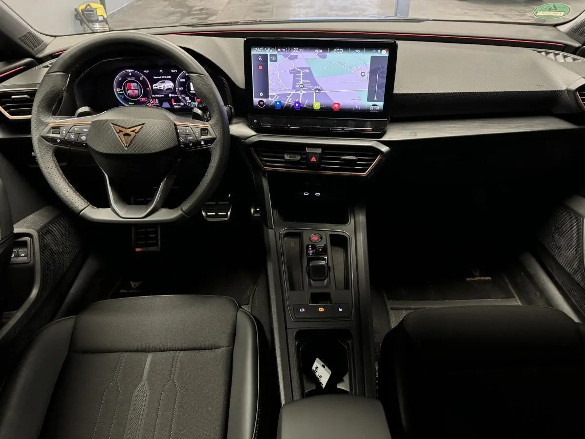 Vue intérieure avant du CUPRA Leon Sportstourer 2024 avec tableau de bord digital et écran tactile central.