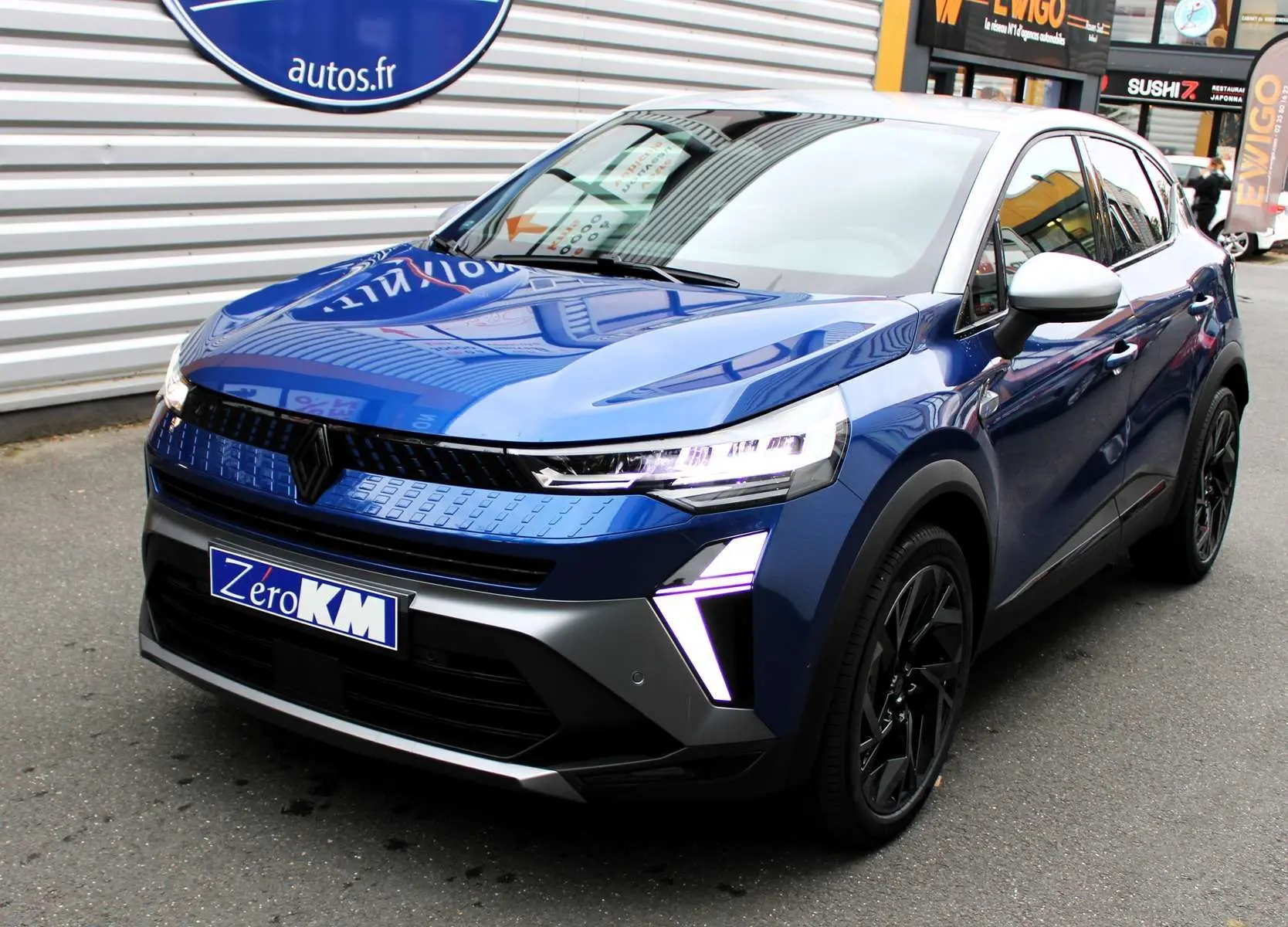 Renault Captur 2025 bleu Iron Metal avec toit gris, vue 3/4 avant mettant en valeur ses feux LED distinctifs.