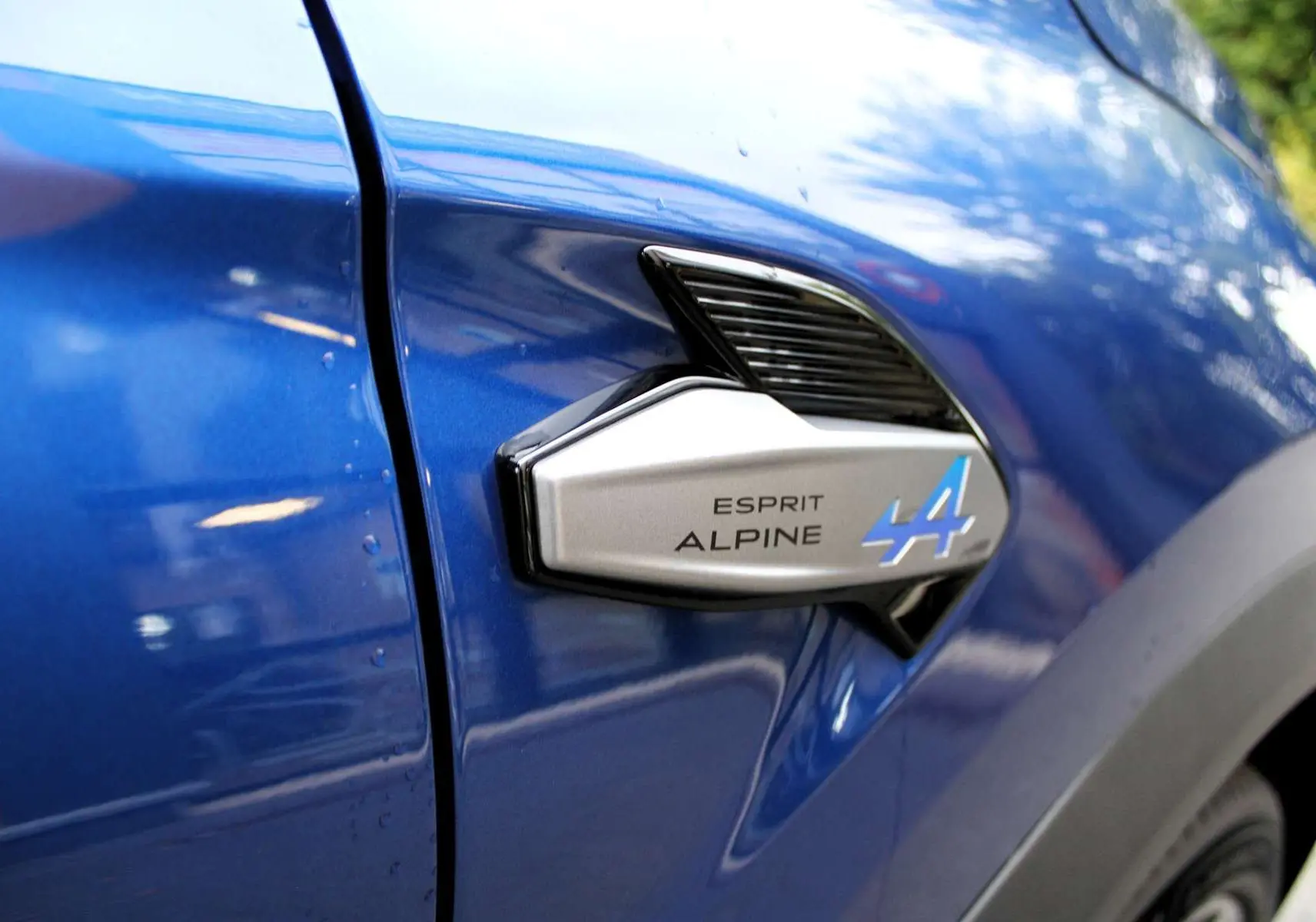 Détail de l'insigne Esprit Alpine sur la portière côté gauche d'un Renault Captur bleu Iron Metal.