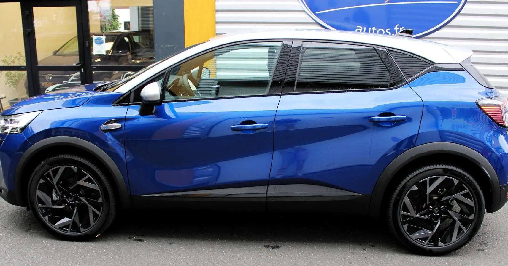 Profil côté gauche d'un Renault Captur 2025 bleu Iron Metal avec toit gris et jantes noires stylisées.