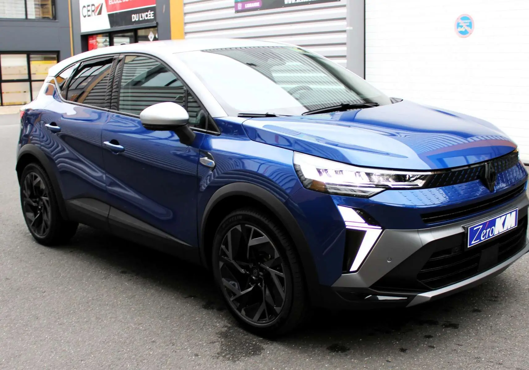 Renault Captur 2025 bleu Iron Metal avec toit gris, vue 3/4 avant mettant en valeur ses feux LED distinctifs.