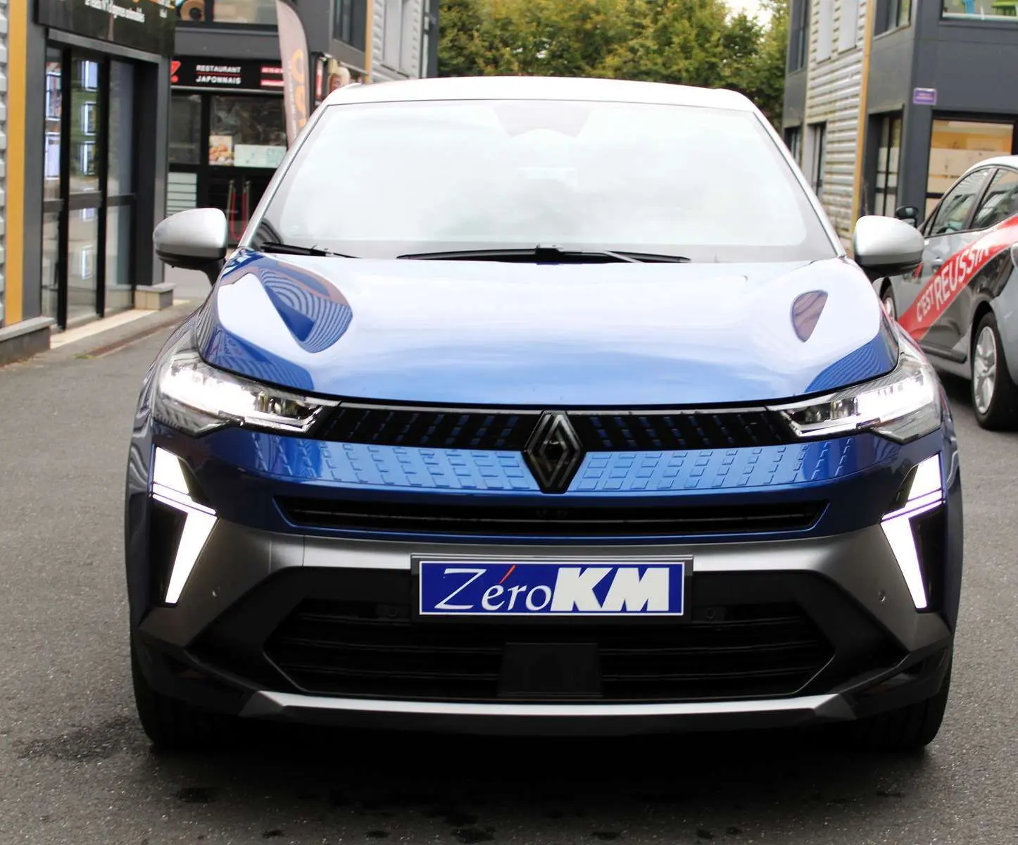 Vue frontale du Renault Captur 2025 bleu Iron Metal avec toit gris et feux LED en forme de V allumés.
