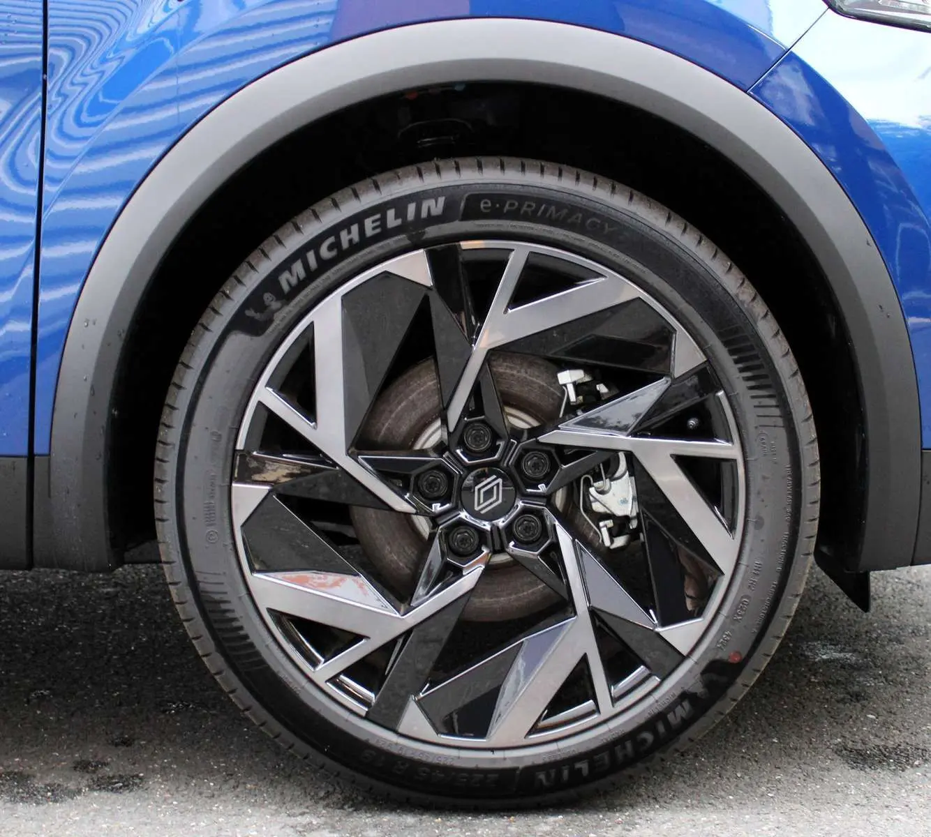 Gros plan sur la roue avant droite du Renault Captur bleu Iron Metal avec jante alliage noir et argent.