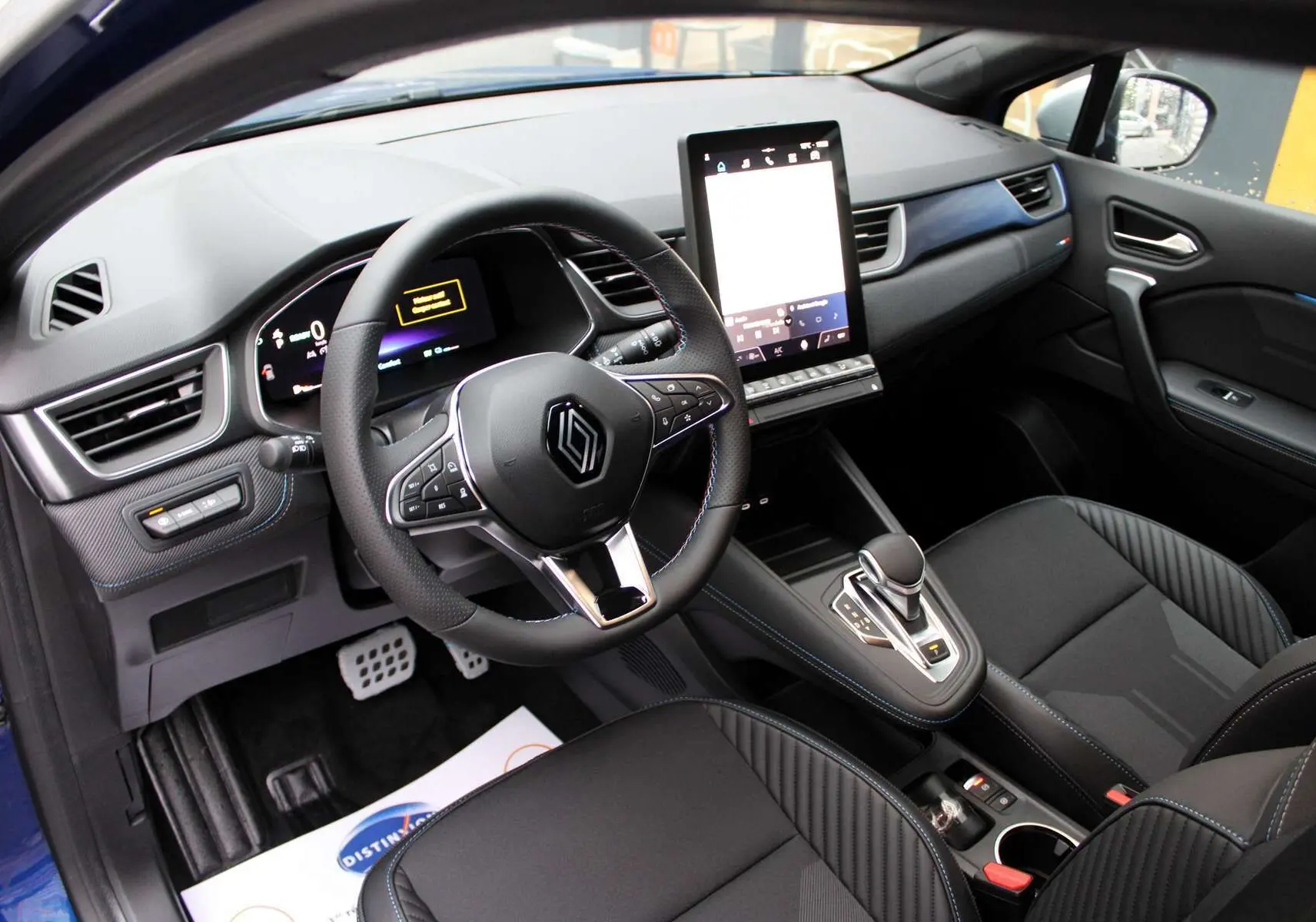 Intérieur du Renault Captur 2025, vue côté conducteur, tableau de bord moderne avec écran tactile vertical et sellerie noire.