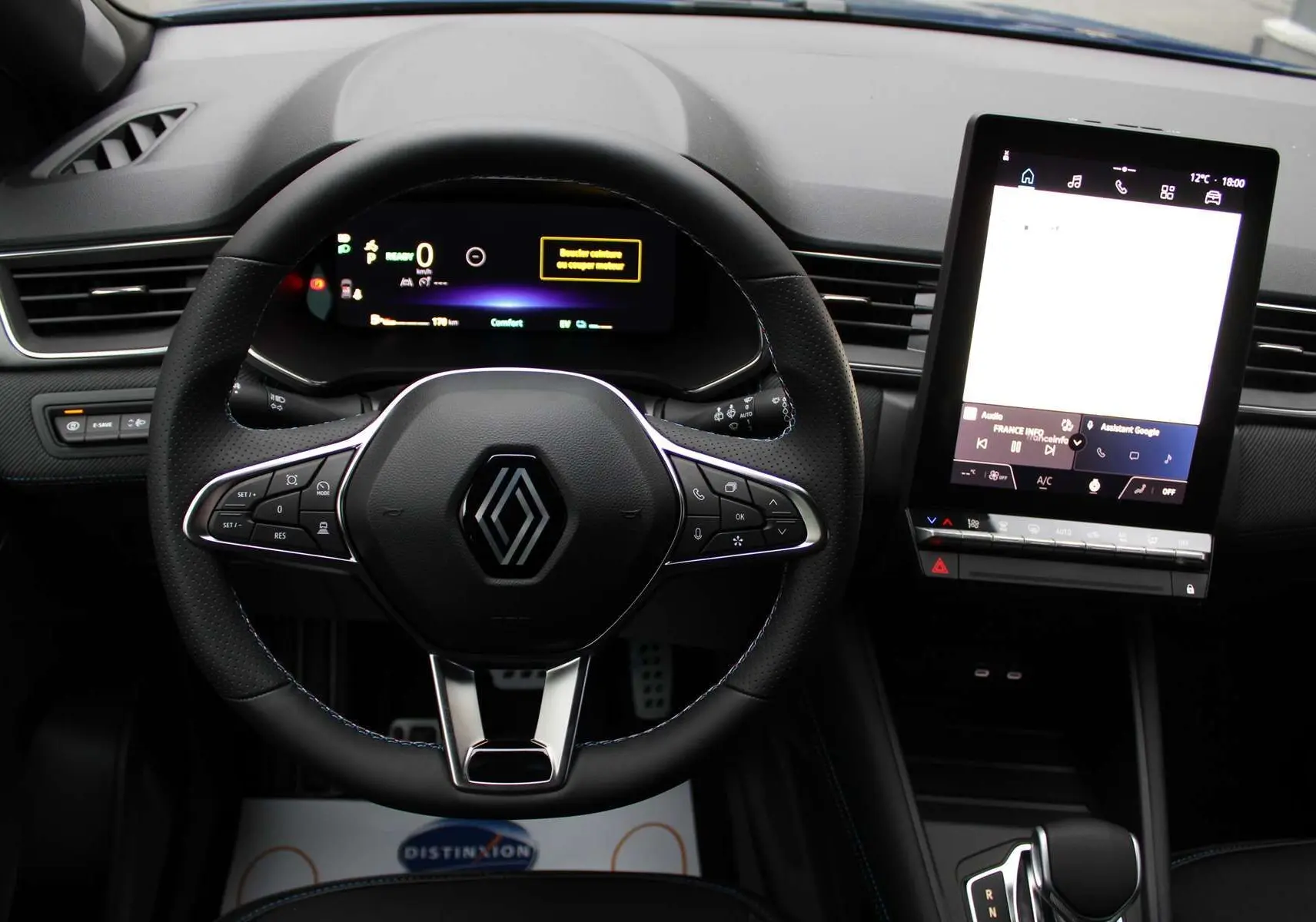 Vue intérieure centrée sur le volant et l'écran tactile vertical du tableau de bord du Renault Captur hybride 2025.