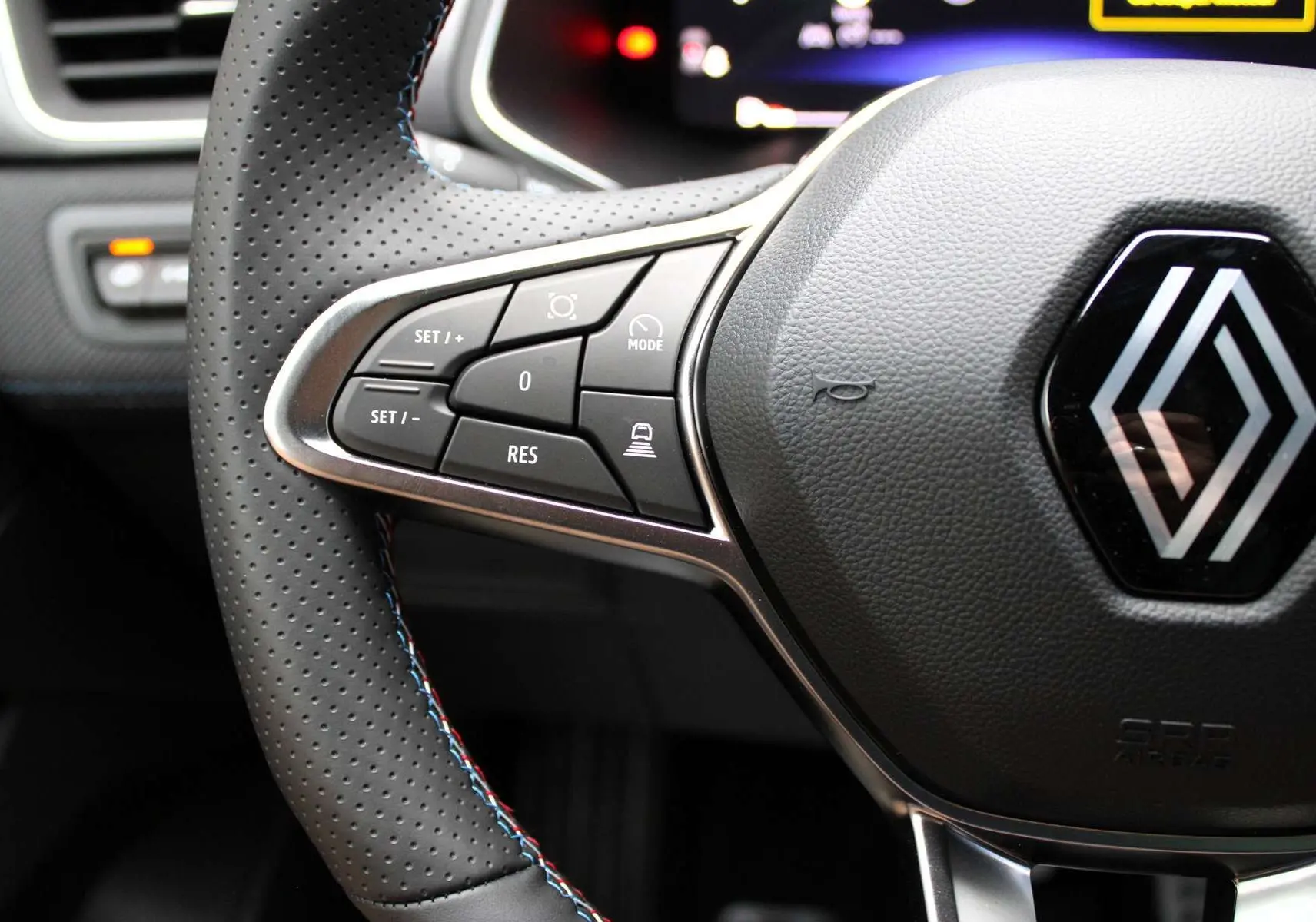 Gros plan sur le volant en cuir perforé avec commandes intégrées et logo Renault au centre du Renault Captur 2025.