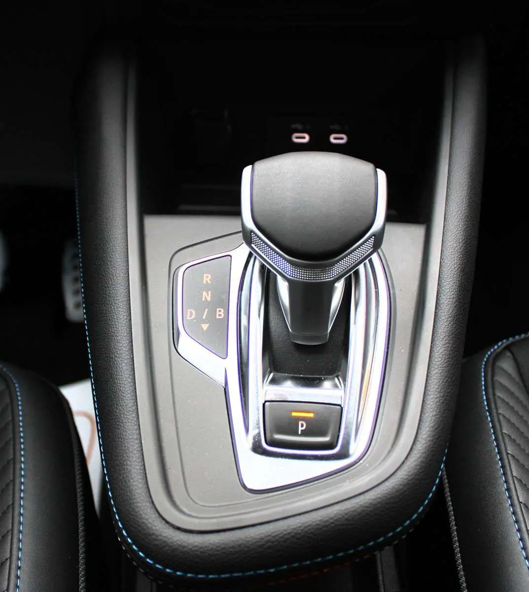 Le levier de vitesses automatique du Renault Captur 2025, entouré de cuir noir avec surpiqûres bleues.