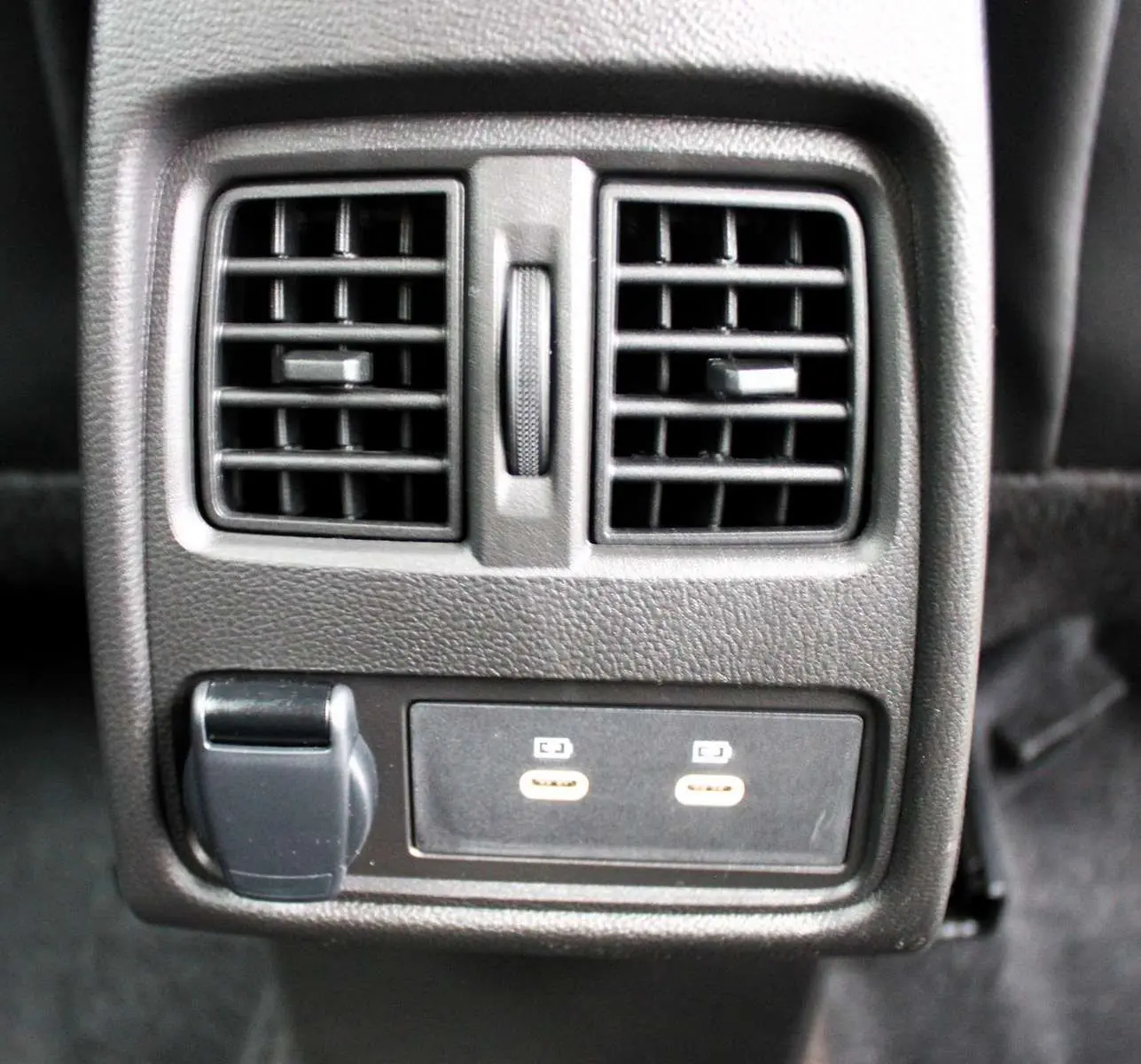 Gros plan sur la console arrière noire du Renault Captur 2025 avec deux bouches d'aération et ports USB visibles