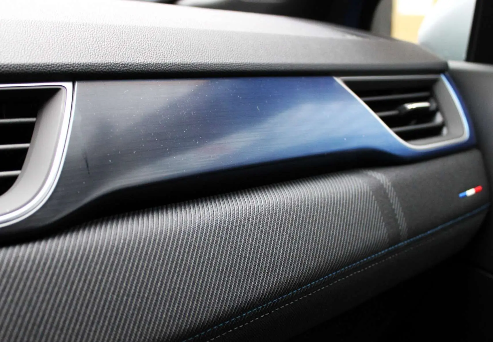 Détail de la planche de bord du Renault Captur 2025 avec insert bleu et surpiqûres bleues côté passager.