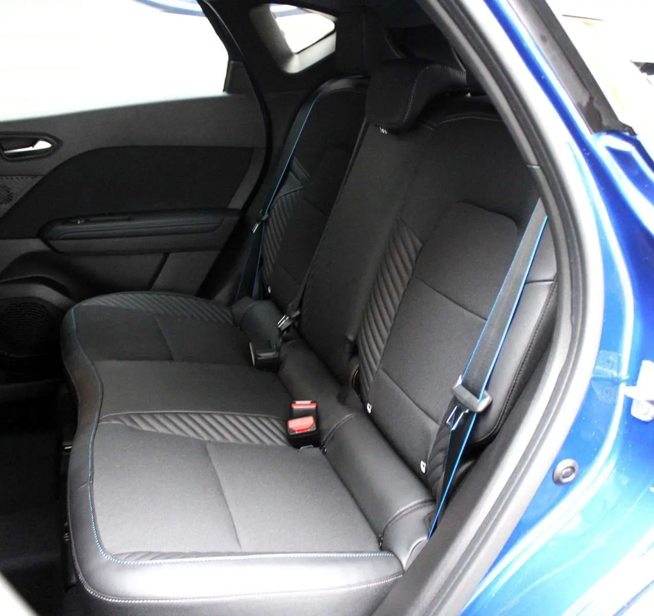 Vue intérieure côté droit des sièges arrière noirs avec surpiqûres bleues du Renault Captur 2025 bleu iron metal toit gris.