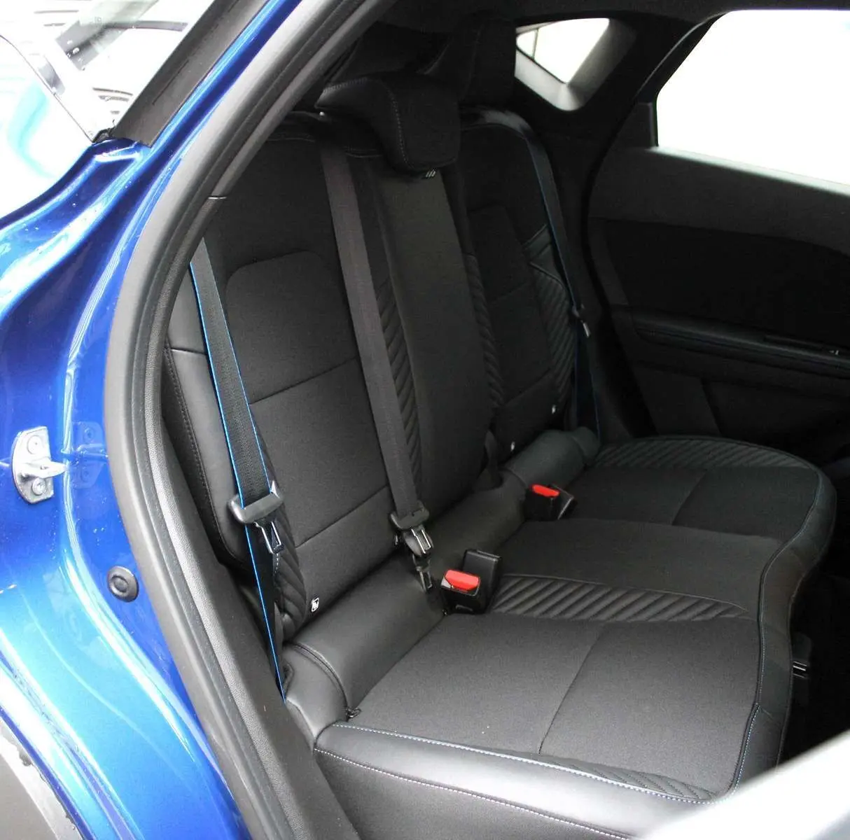 Vue intérieure côté gauche des sièges arrière noirs avec surpiqûres bleues du Renault Captur 2025 bleu iron metal.
