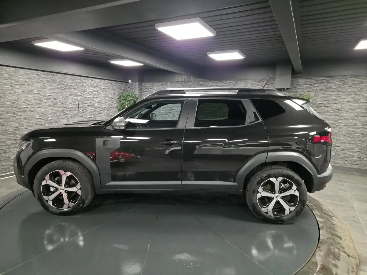 Vue de profil côté gauche du Dacia Duster 1.6 Hybrid 140 Journey noir nacré avec jantes alliage 18 pouces diamantées.